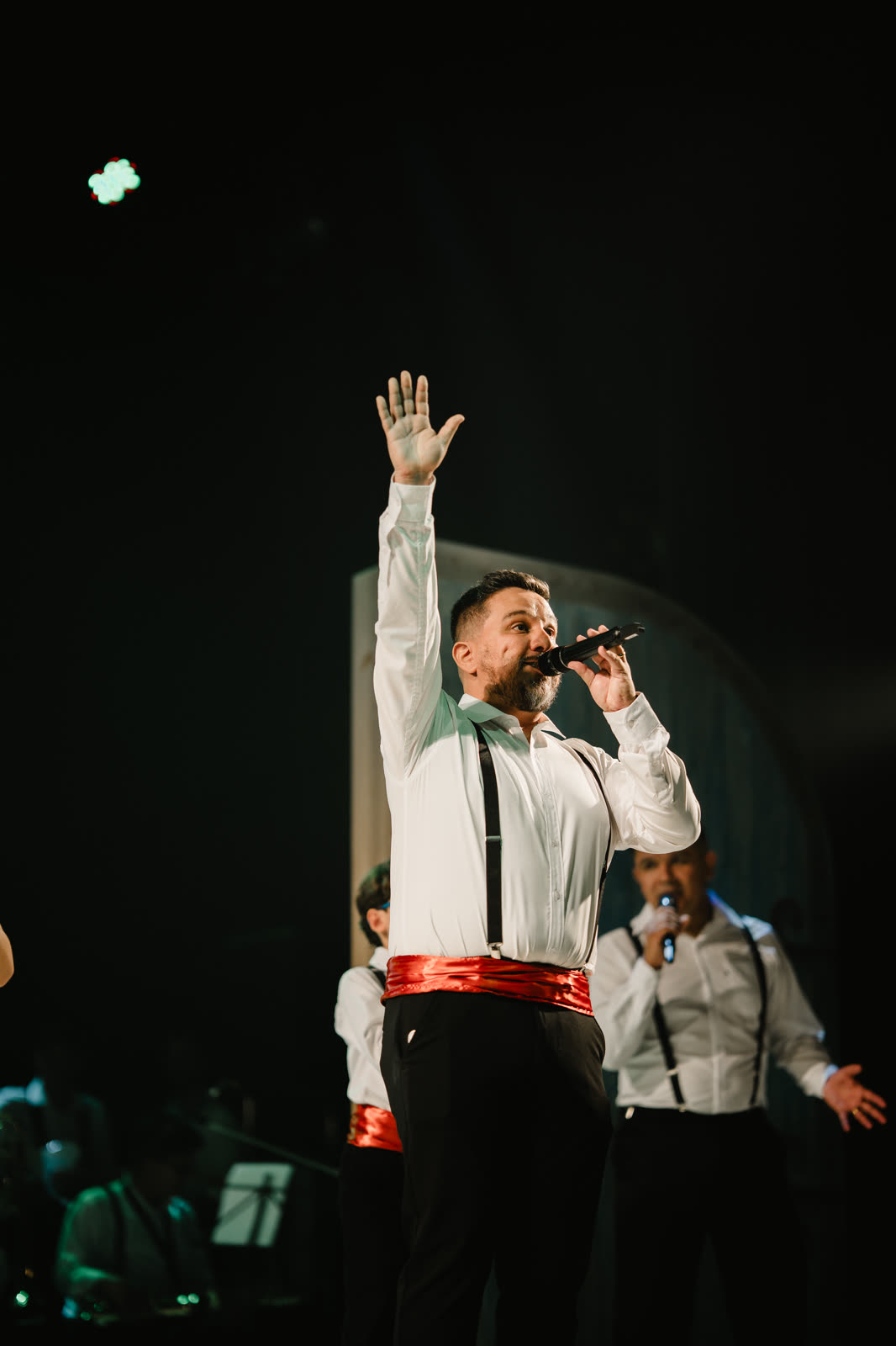 Cantor com a mão erguida durante um momento de adoração no palco