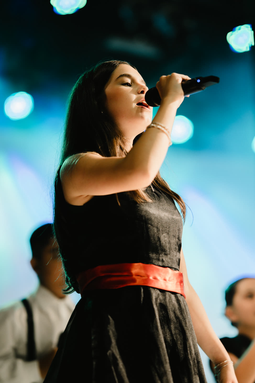 Jovem cantando ao microfone sob luzes azuis