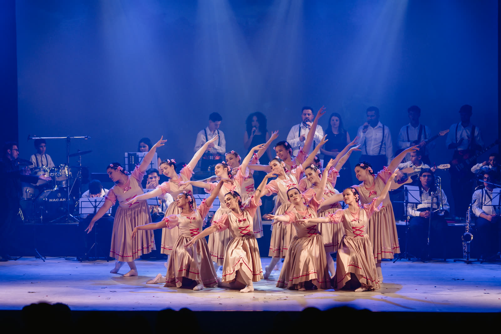 Grupo de dança de dourado com a banda ao fundo