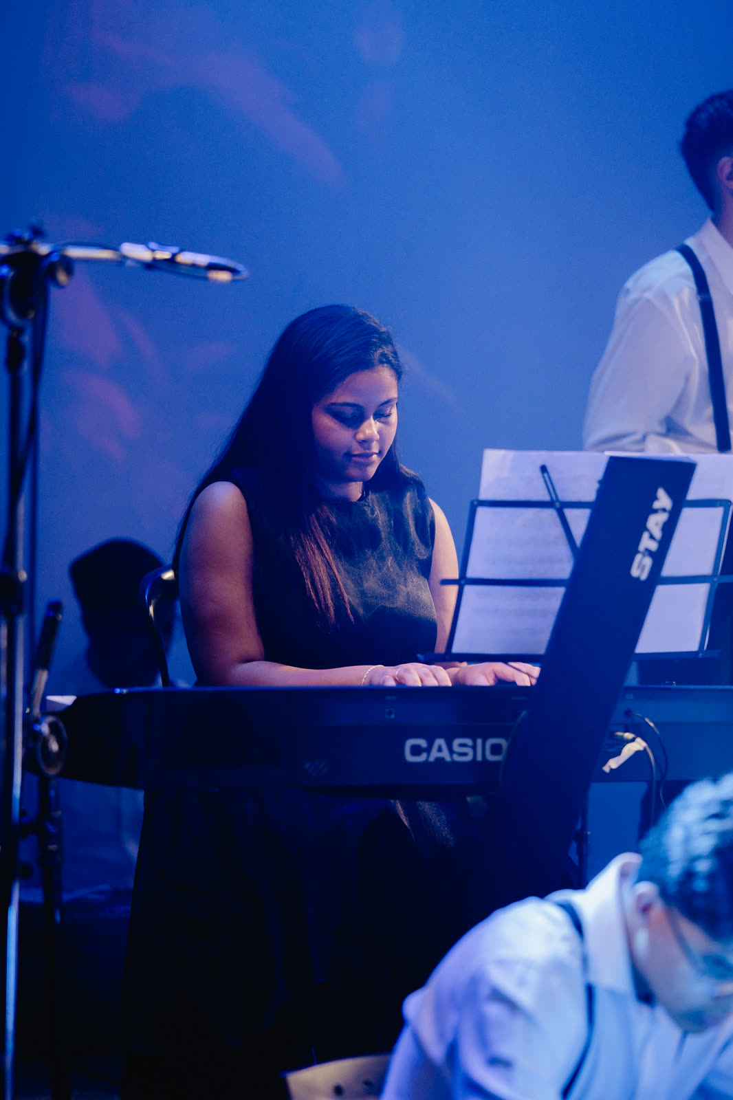 Aluna tocando teclado com a partitura à frente
